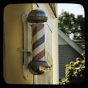 Classic barbershop pole on a yellow wall.