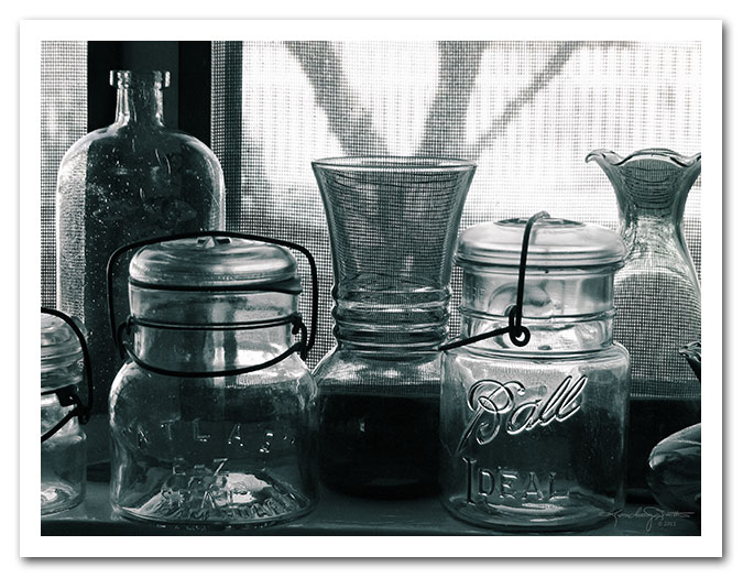 E-Z and Ideal - monochrome glass canning jars and vases on a window sill in morning light.