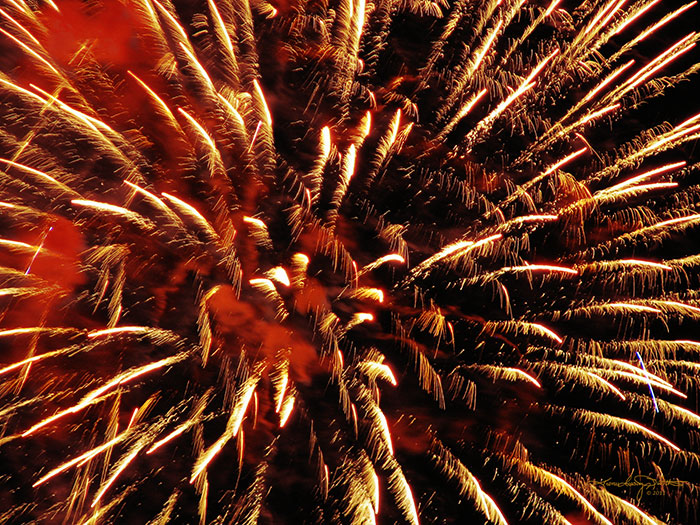 close up of golden fireworks explosion with red smoke